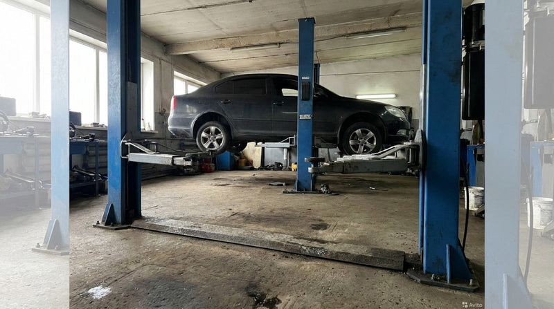 Two-post vehicle lift with a floor baseplate bar running between the columns