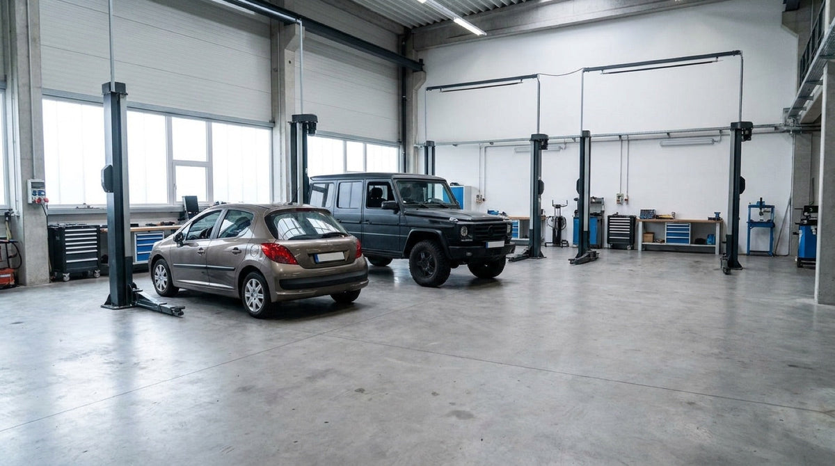 A small hatchback and a large SUV side by side in a workshop showing the size difference