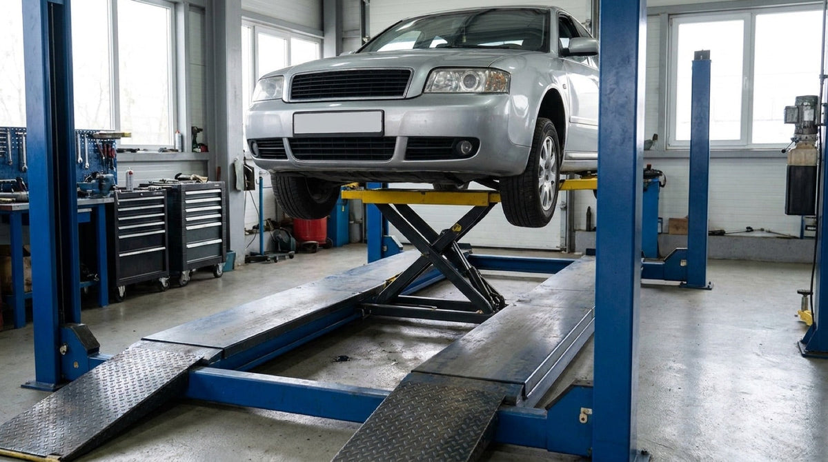 Jacking beam mounted between the runways of a four-post lift raising a car's front wheels